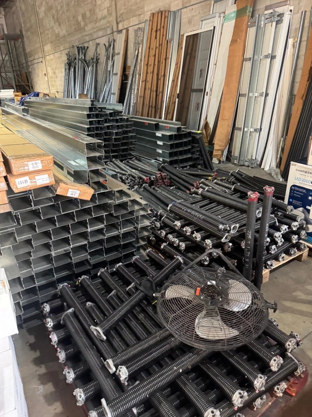Stacks of steel garage door track and hardware stored in a supply area
