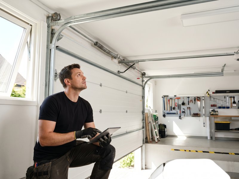 Technician checking an opener control panel inside a garage